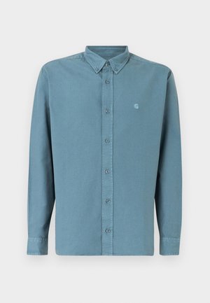 Camisa de botones azul claro con mangas largas, cuello puntiagudo y un pequeño logotipo en el lado izquierdo del pecho. Fabricada con una tela suave y lisa.