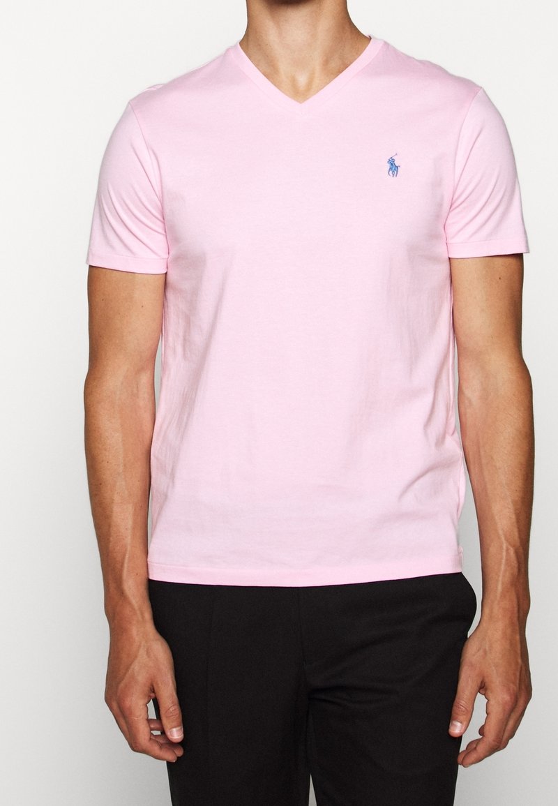 T-shirt fucsia a scollatura a V in cotone. Maniche corte, design aderente, con un piccolo logo blu sul petto sinistro. Texture liscia.