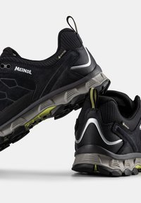 Černé turistické boty s svrchním materiálem z semiše a síťoviny, šedou mezipodešví a strukturovanou gumovou podrážkou. Výrazné akcenty v limetkově zelené a stříbrné barvě.