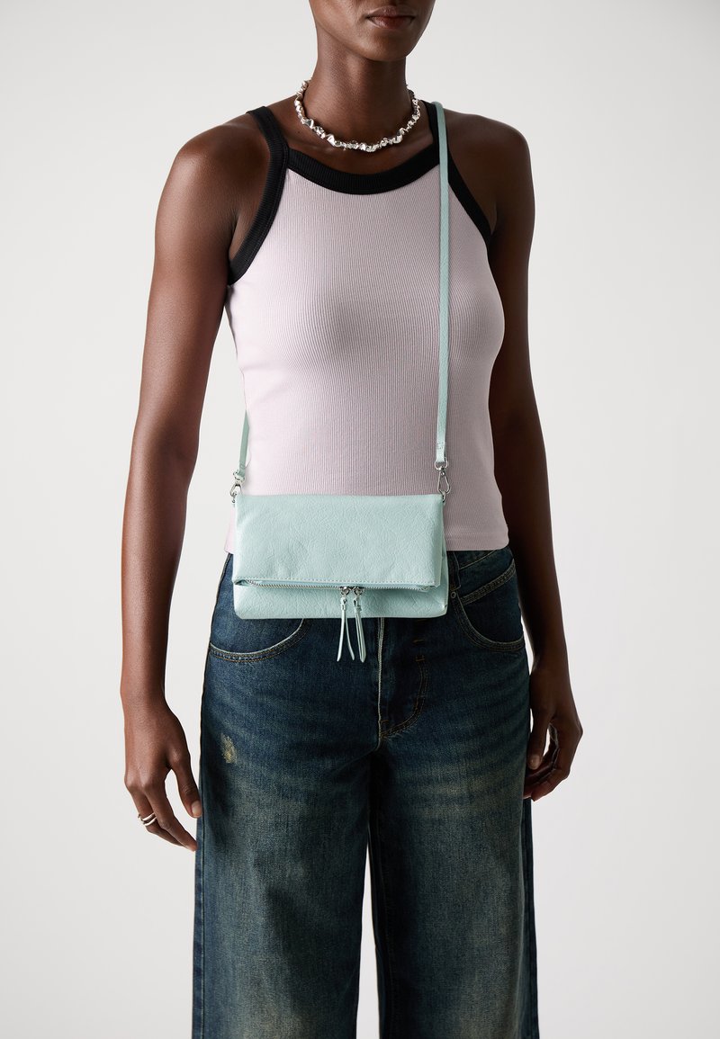 Borsa a tracolla verde menta realizzata in materiale testurizzato, con design a pieghetta e chiusura con zip, dotata di una lunga tracolla regolabile.
