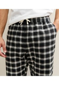 Plaid pajama pants in black and white, made of soft fabric with an elastic waistband and drawstring, featuring a checked pattern.