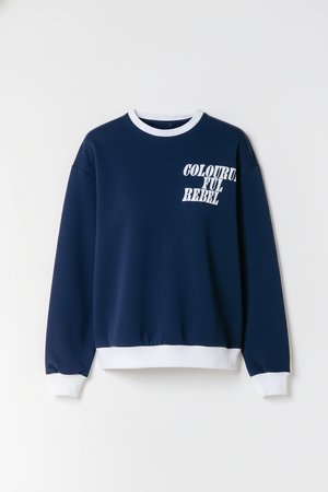 Tumesinine pusa valge soonikuga krae ja varrukaotsadega. Vasakul rinnal on valgete tähtedega kiri "COLORFUL REBEL". Pehme kangapind.