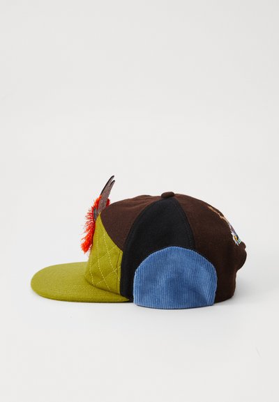 Bunte Kappe mit Abschnitten aus grünem, braunem, schwarzem und blauem Cord. Hat ein strukturiertes Patch und ein orangefarbenes Dekorationselement oben.