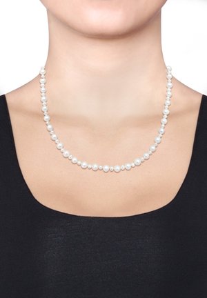 Collier en perles blanches composé de perles rondes de taille uniforme, enfilées en un seul brin, porté sur un haut noir.