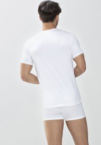 Biały, krótki rękaw t-shirt z klasycznym okrągłym dekoltem, noszony z białymi bokserkami, ukazując gładki materiał i dopasowaną sylwetkę z tyłu.