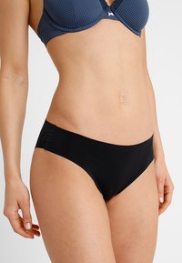 Zwarte bikini broek met een gladde textuur, met een lage taille en naadloze randen voor comfort. Minimalistisch en veelzijdig ontwerp.