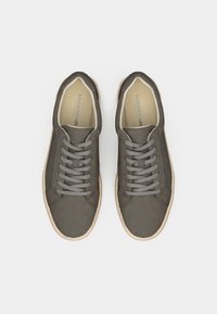 Γκρίζα σουέτ αθλητικά παπούτσια με στρογγυλή μύτη, επίπεδες γκρίζες κορδόνες και ελαφριά μπεζ λαστιχένια σόλα. Διαθέτουν διακριτική σήμανση στο εσωτερικό του παπουτσιού.