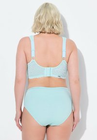 Reggiseno in pizzo azzurro chiaro con spalline regolabili e chiusura a gancio, abbinato a mutandine a vita alta coordinate. Texture liscia e motivo floreale.