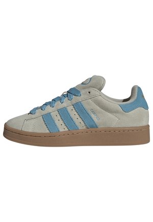 Beżowy niski zamszowy sneaker z jasnoniebieskimi paskami, pasującymi sznurowadłami i brązową gumową podeszwą, widok z boku.