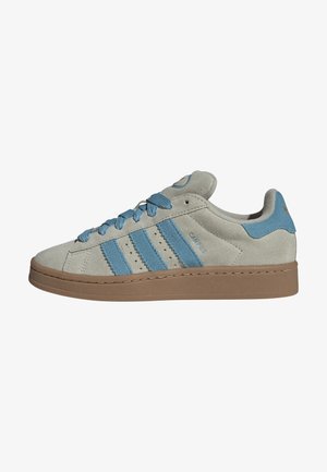 Beżowy niski zamszowy sneaker z jasnoniebieskimi paskami, pasującymi sznurowadłami i brązową gumową podeszwą, widok z boku.