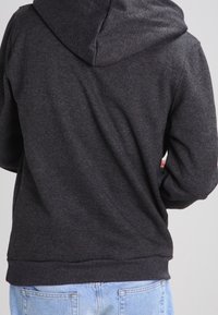 Czarna bluza z kapturem, wykonana z miękkiego materiału. Posiada ściągacze przy mankietach i dolnej krawędzi, prosty design bez dodatkowych wzorów czy ozdób.