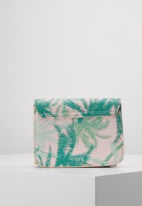 Floral crossbody bag with a pastel pink base, featuring a green palm leaf pattern. Made of synthetic material with a fold-over flap design.