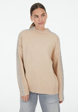 Beige gestrickter Pullover mit geripptem Saum und grauen strukturierten Akzenten an den Ärmeln. Verfügt über einen hohen Kragen und eine lockere Passform.