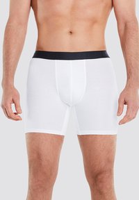 Weiße Boxer-Briefs aus glattem Stoff mit einem schwarzen elastischen Bund. Sie verfügen über ein körpernahes Design und kontrastierende Nähte.
