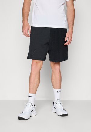 Black athletic shorts with a textured fabric, featuring a contrasting smooth panel and white stitching details. Worn with white shoes and socks.
