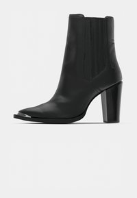 Bottine en cuir noir avec un bout pointu, des panneaux latéraux élastiques et un talon bloc noir brillant. Comprend un accent chrome sur le bout.