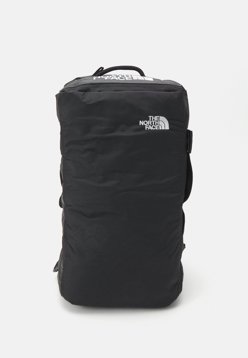 Sac à dos rectangulaire noir avec poignée supérieure et logo The North Face blanc sur les parties avant et supérieure.