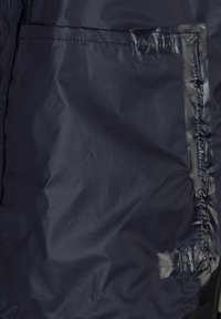 Veste imperméable bleu marine avec une texture lisse, dotée d'une fermeture éclair et d'une poche à rabat à l'avant pour le rangement.