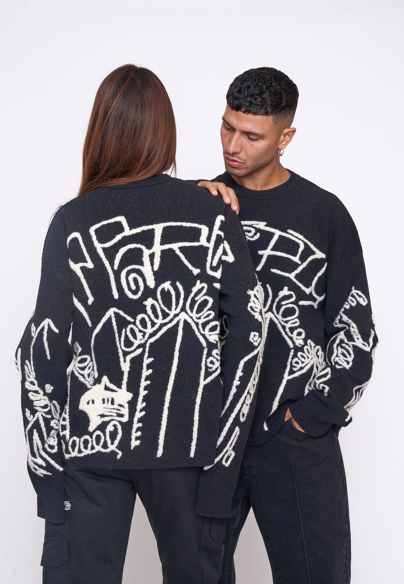 Pulover negru cu modele abstracte albe, are mâneci lungi, guler rotund și un finisaj texturat. Modelele sunt variate și intricate.