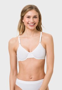 White bra with smooth, molded cups and adjustable straps. Simple design with no embellishments; made from lightweight, stretchy material.