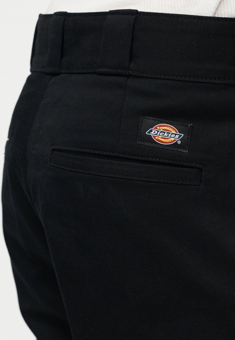 Tasca posteriore dei pantaloni neri Dickies che mostra la toppa con il logo del marchio e gli occhielli per cintura sulla vita.