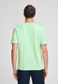 Kortärmad T-shirt i ljusgrön bomull, med rund halsringning och en avslappnad passform, med en jämn textur och inga synliga mönster.