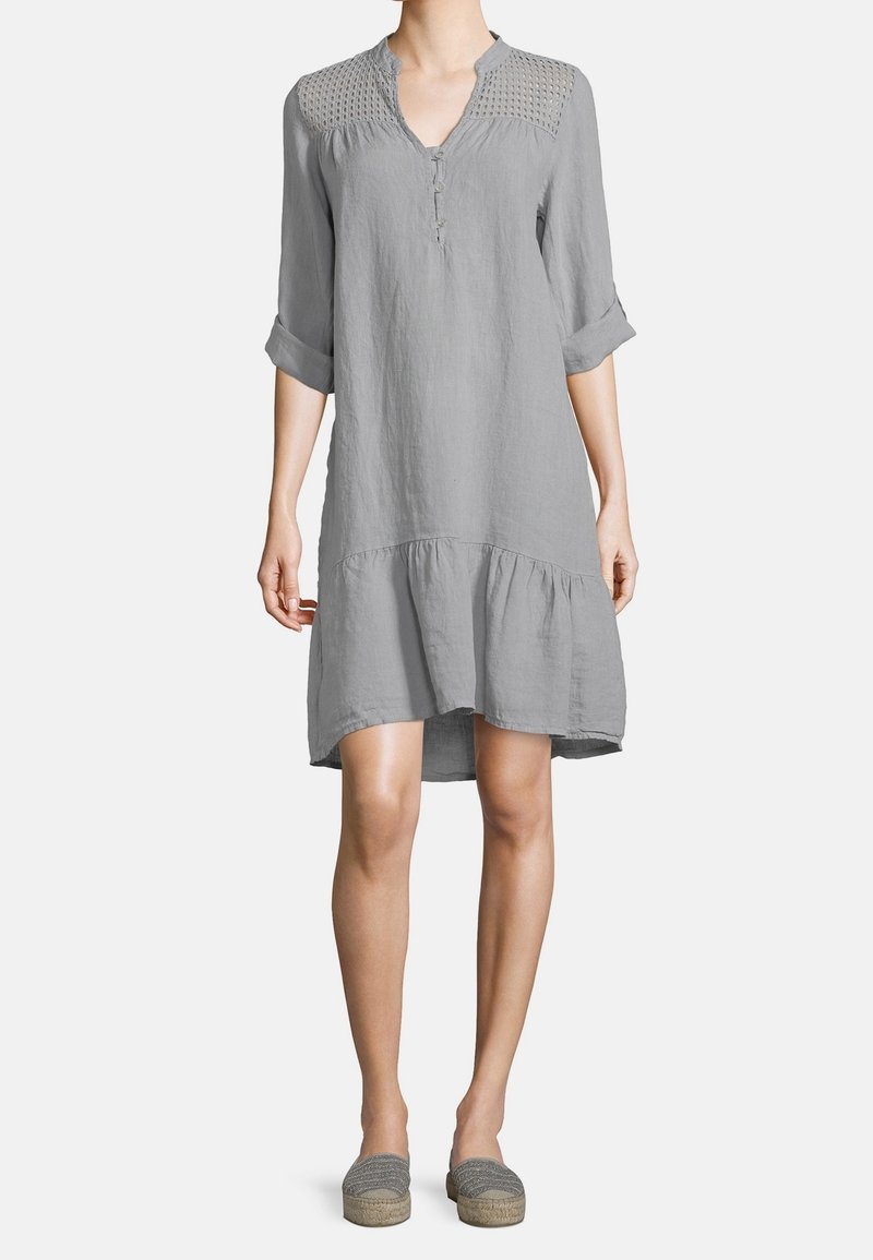 Abito in lino grigio con scollatura a V, apertura con bottoni e dettagli in crochet testurizzato sulle spalle. Presenta un orlo a balze e maniche arrotolate.