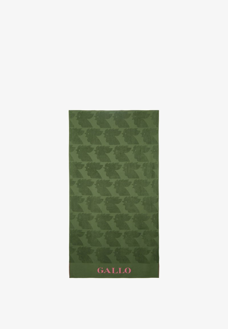 Asciugamano verde con un motivo ripetuto di teste stilizzate, con il testo rosa "GALLO" in basso. Tessuto morbido e texturizzato.