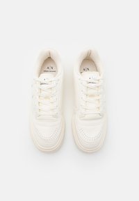 Weiße Ledersneaker mit Schnürdesign, perforierter Zehenpartie und leichtem Plateau. Markenlogo auf der Zunge gedruckt. Weiche Textur.