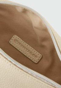 Borsa in pelle crema con una superficie liscia, chiusura con zip e foderatura in tessuto beige con un'etichetta marchiata all'interno.