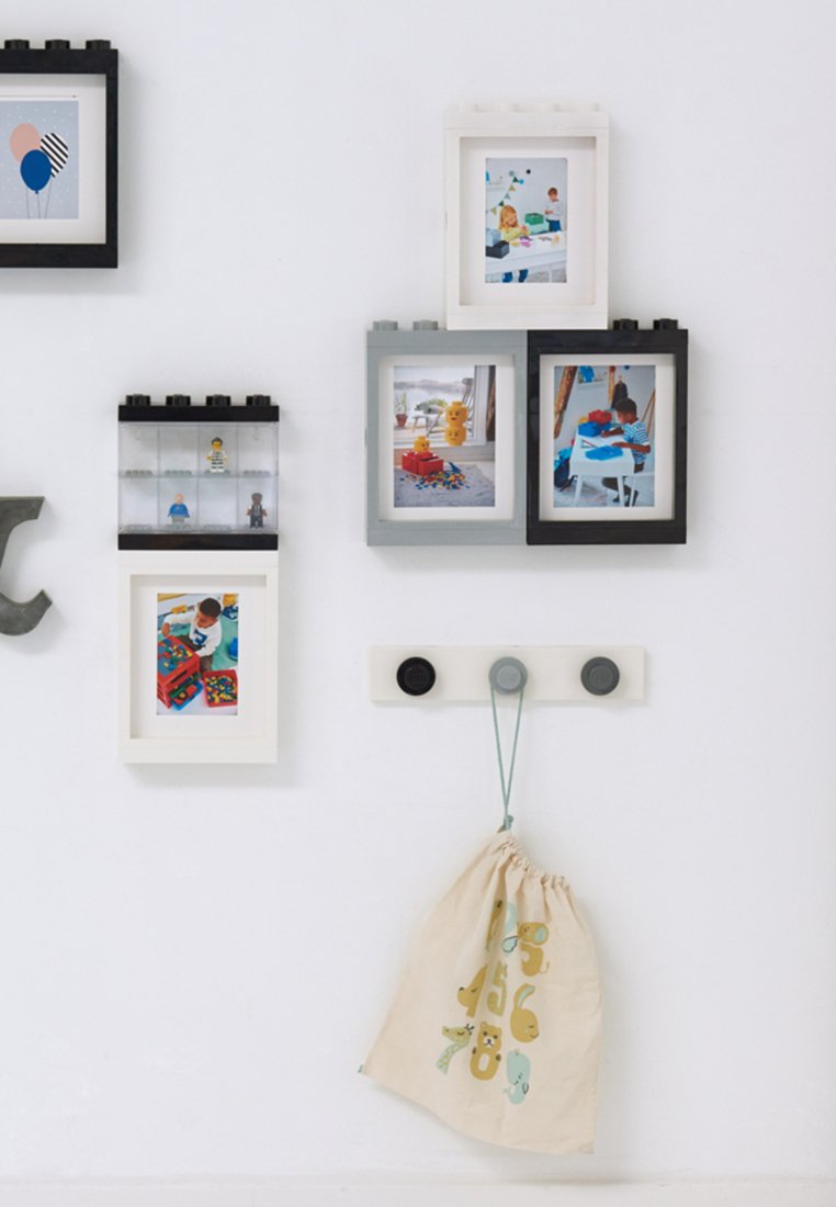 Collage de cinco marcos de fotos en negro, blanco y gris, junto a una bolsa de tela con cordón de color beige con ilustraciones de animales, montada en una pared blanca.