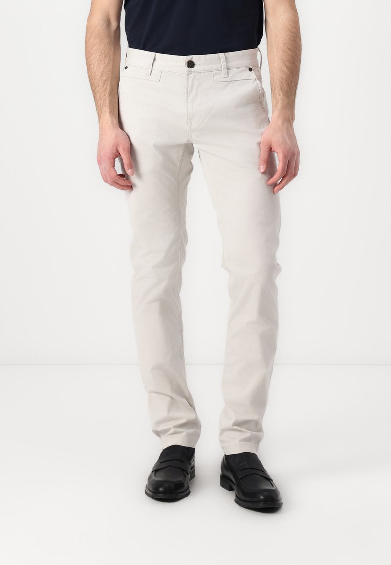 Helle beige Slim-Fit-Hosen aus Baumwolle. Mit Gürtelschlaufen, Taschen vorne und einem Knopfverschluss. Glatte Textur, minimales Design.