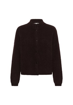 Femme portant un pull duveteux marron foncé boutonné, un pantalon ample marron foncé à jambes larges, une ceinture marron et des chaussures marron sur fond blanc.