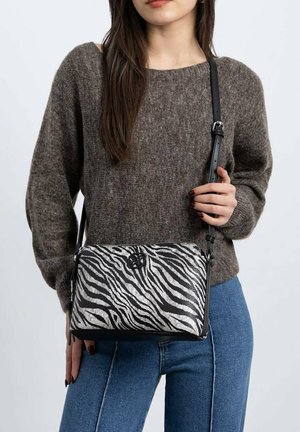 Bolso de hombro con estampado de cebra y cierre de cremallera, con una correa negra y acentos en negro. Fabricado con un tejido texturizado en negro y plata.