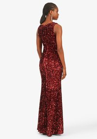 Rotes Pailletten-Abendkleid mit eng anliegendem Oberteil und langem, fließendem Rock. Mit ärmellosem Design und einem runden Rückendetail ausgestattet.