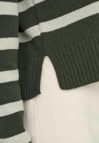 Grön och vit randig stickad tröja med texturerad tyg. Har en ribbad fåll och sidsprund. Mjuk, avslappnad design.