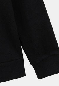 Tissu de sweatshirt noir avec une finition douce et texturée. Présente des manches avec poignets et un col rond. Design simple et minimal.