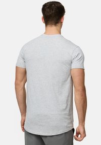  Lichtgrijs katoenen t-shirt met korte mouwen, ronde hals en een iets langere achterzoom. Gladde textuur en eenvoudig ontwerp.