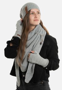 Grijze gebreide beanie, sjaal en vingervrije handschoenen gemaakt van gestructureerde stof. De sjaal hangt losjes, heeft een accentknop en lussen.