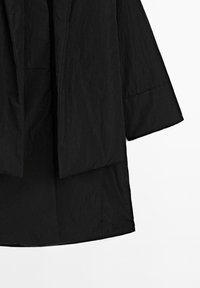 Black, wrinkled fabric coat with a loose design, featuring wide sleeves and an open front. Hemline reaches mid-thigh. No visible hardware.