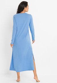 Abito maxi blu a maniche lunghe con spacco laterale, caratterizzato da una vestibilità comoda e un tessuto morbido e liscio. Design semplice, senza motivi o accenti visibili.