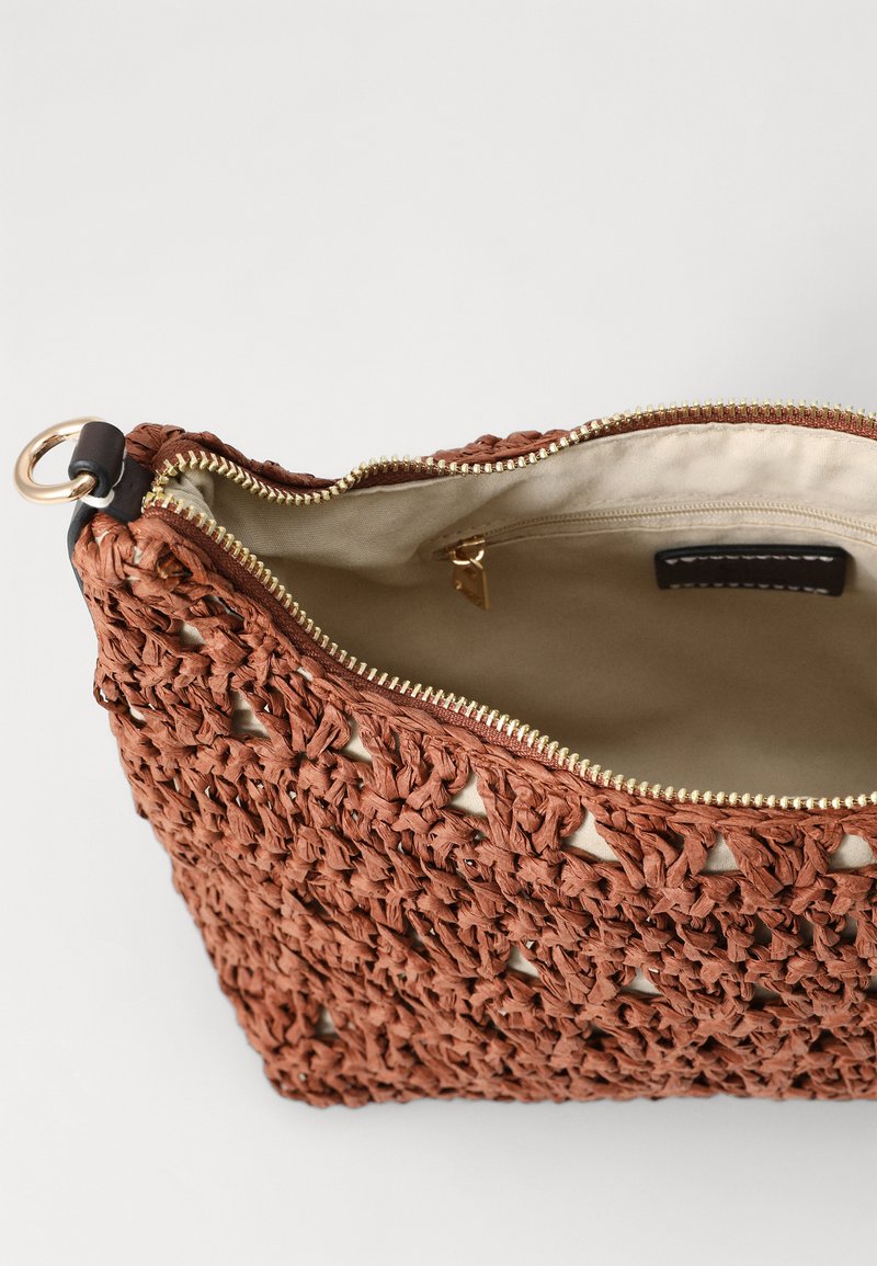 Bolsa tejida marrón hecha de material texturizado, con un cierre de cremallera en la parte superior con accesorios dorados y un forro beige. El interior incluye un bolsillo con cremallera.