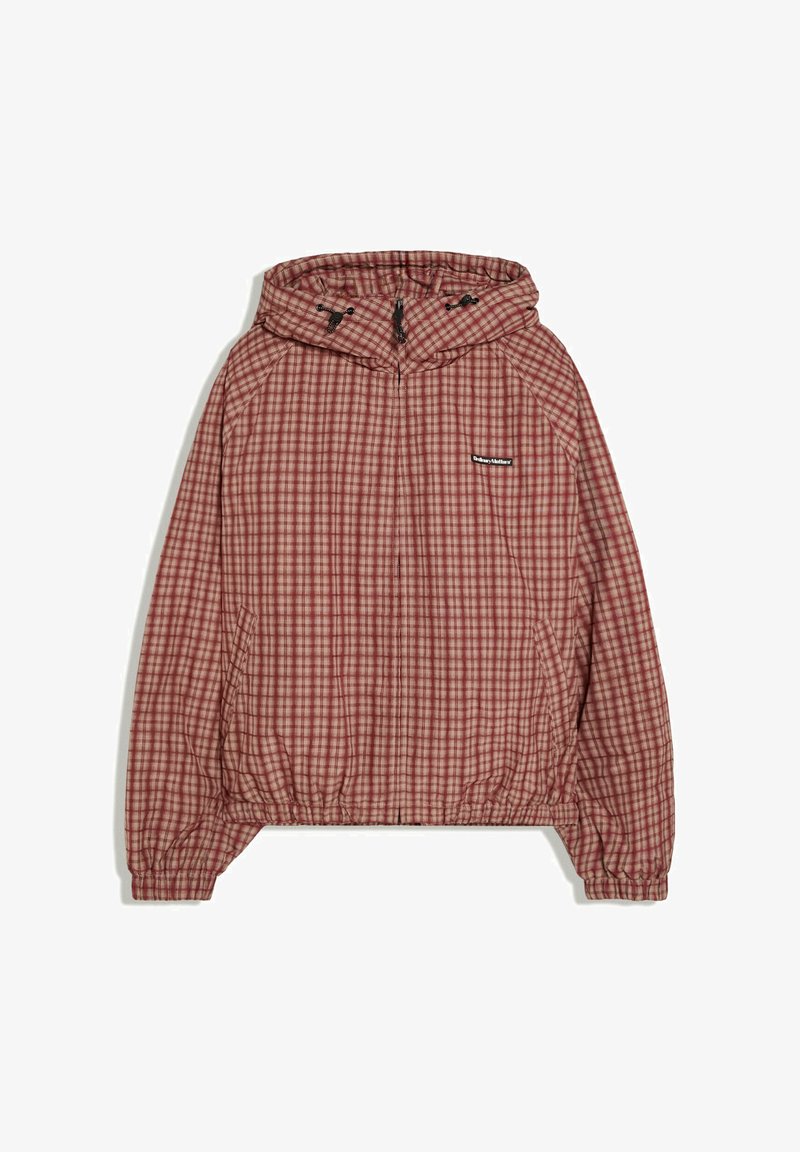 Veste à capuche à carreaux rouge et beige avec fermeture éclair frontale, poignets et bas élastiques, et petite étiquette noire de la marque sur la poitrine.