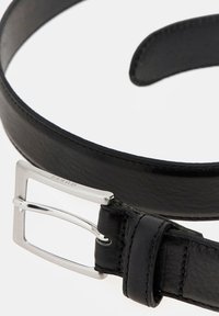 Cinturón de cuero negro con textura suave, presenta una hebilla de metal plateada y costuras discretas. Diseño clásico con acentos mínimos.