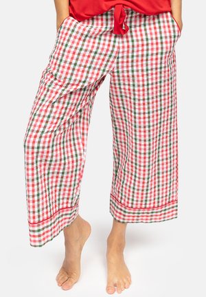 Pantalones anchos de cuadros rojos, blancos y verdes con bolsillos, usados descalzo con un top rojo anudado.