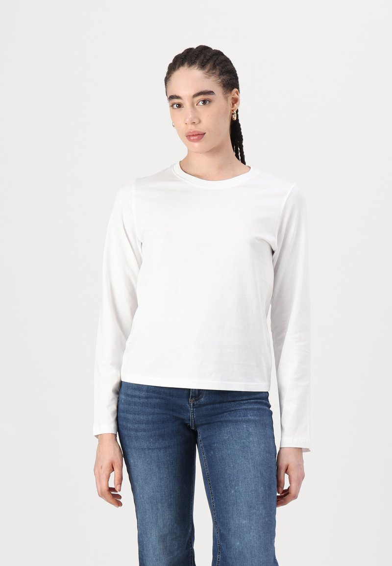 Langærmet, rundhalset hvid t-shirt lavet af blød bomuld, med en afslappet pasform og flade sømme, parret med blå jeans.