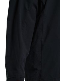 Veste noire à manches longues avec couture visible et tissu texturé sur le panneau latéral, vue en gros plan.