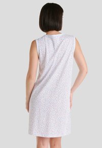 El vestido de algodón sin mangas presenta un fondo blanco con un patrón floral multicolor, un cuello de rayas en contraste y una textura suave.