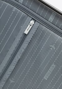 Šedá cestovní taštička s síťovanou panelem a zipovým uzávěrem, s vodorovnými pruhy a hladkým povrchem. Odolná tkanina s jemnými detaily.