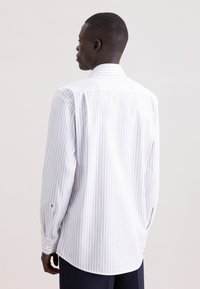 Camicia da uomo bianca a maniche lunghe con sottili righe verticali grigio chiaro, polsini con bottoni e orlo arrotondato. Tessuto dalla texture liscia e colletto classico.